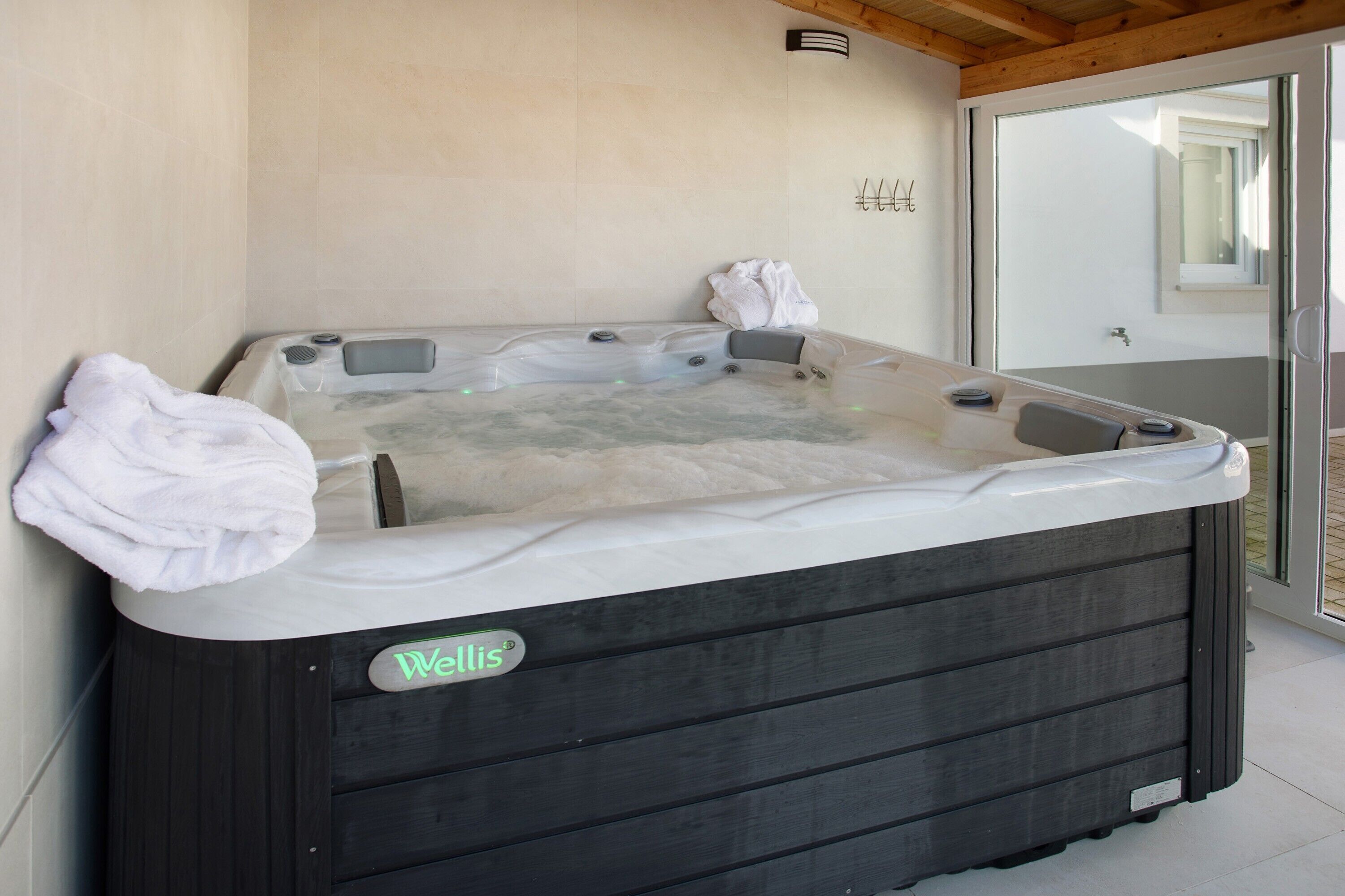Un jacuzzi con el rótulo 'Wells', una toalla al lado y una puerta de vidrio que da a un espacio al aire libre.