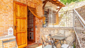 A brick building with a wooden door, a balcony with metal railings, and a table with chairs outside. - Holiday Home 'Seaview Camaiore' with Sea View, Private Pool and Wi-Fi (Camaiore)