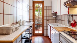 A kitchen with white cabinets, a wooden door, a gas stove, and a tiled backsplash. - Holiday Home 'Seaview Camaiore' with Sea View, Private Pool and Wi-Fi (Camaiore)