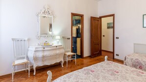 A bedroom with a wooden floor, a white dresser, a mirror, a bed with floral bedding, and a chandelier. - Holiday Home 'Seaview Camaiore' with Sea View, Private Pool and Wi-Fi (Camaiore)