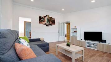 A living room with a grey sofa, a coffee table, a flat-screen TV, and a cactus plant.