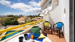 A balcony with a pool, chairs, and a table with a plate, glass, and napkin. - Apartment 'Montechoro' with Balcony and Wi-Fi (Albufeira)