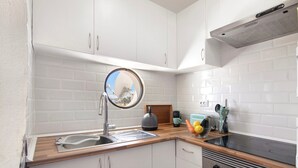 A kitchen with white cabinets, a sink, a stove, and a microwave. - Apartment 'Montechoro' with Balcony and Wi-Fi (Albufeira)