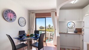 A dining area with a table, chairs, and two wall clocks. - Apartment 'Montechoro' with Balcony and Wi-Fi (Albufeira)