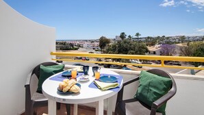 A balcony with a table set for breakfast, overlooking a coastal town. - Apartment 'Montechoro' with Balcony and Wi-Fi (Albufeira)