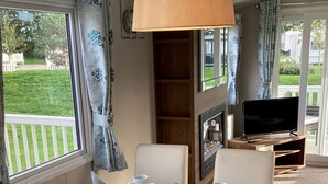 A dining area with a table set for four, a television, and a fireplace. - Immaculate 8-bed Cabin in Tattershall Lake (Lincoln)
