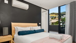 A modern hotel room with a large bed, a bedside table, a lamp, and a view of the city through a large window. - The Warwick 306 (Cape Town)