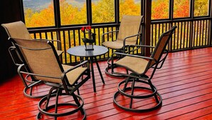 Eine Terrasse mit Korbstühlen und einem kleinen Tisch, mit Blick auf eine reizvolle Herbstlandschaft.