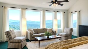 Ein Schlafzimmer mit einem großen Bett, einem Sofa, zwei Sesseln, einem Couchtisch und Bergblick.