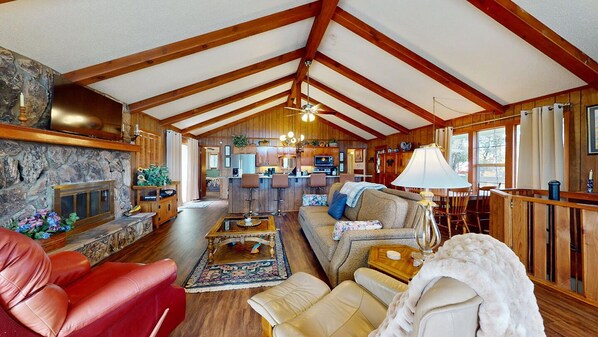 A spacious living room with a fireplace, a kitchen in the background, and a dining area. - Family Friendly Ruidoso Cabin 5 Bdrm Fireplace VIEWS, PRIVACY EV Charger (Ruidoso)