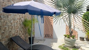A poolside area with lounge chairs, a blue umbrella, and potted plants. - Tranquil Beachside Retreat with Private Pool in Garabito (Garabito)