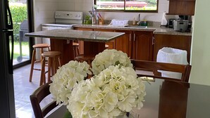 A kitchen with a dining area, a window with a view, and a vase with flowers on the table. - Tranquil Beachside Retreat with Private Pool in Garabito (Garabito)