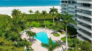 A resort with a pool surrounded by palm trees, a beach view, and a multi-story building. - Beachfront 3BR/3BA condo with heated pool, Wi‑Fi, and full kitchen. (Marco Island)