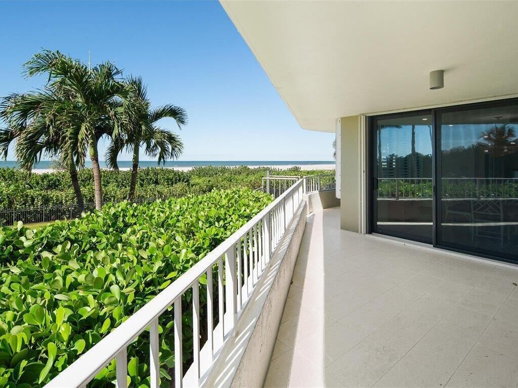 Een balkon met uitzicht op het strand en palmbomen.