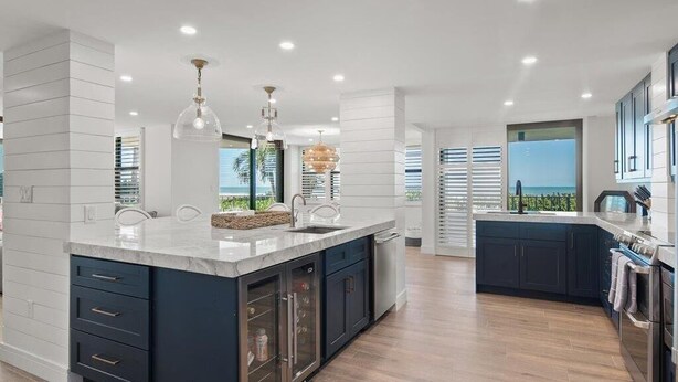 A modern kitchen with a large island, built-in appliances, and a view of the ocean. - Beachfront 3BR/3BA condo with heated pool, Wi‑Fi, and full kitchen. (Marco Island)