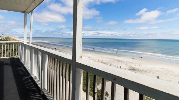 Un balcon avec vue sur une plage et l’océan.