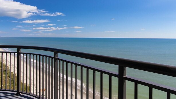 Un balcon avec vue sur l’océan et la plage.