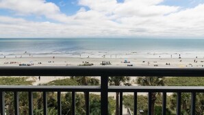 A beach view from a balcony with a railing, palm trees, and the ocean. - Oceanfront Luxury Four Bedroom Condo 3rd Floor (Myrtle Beach)