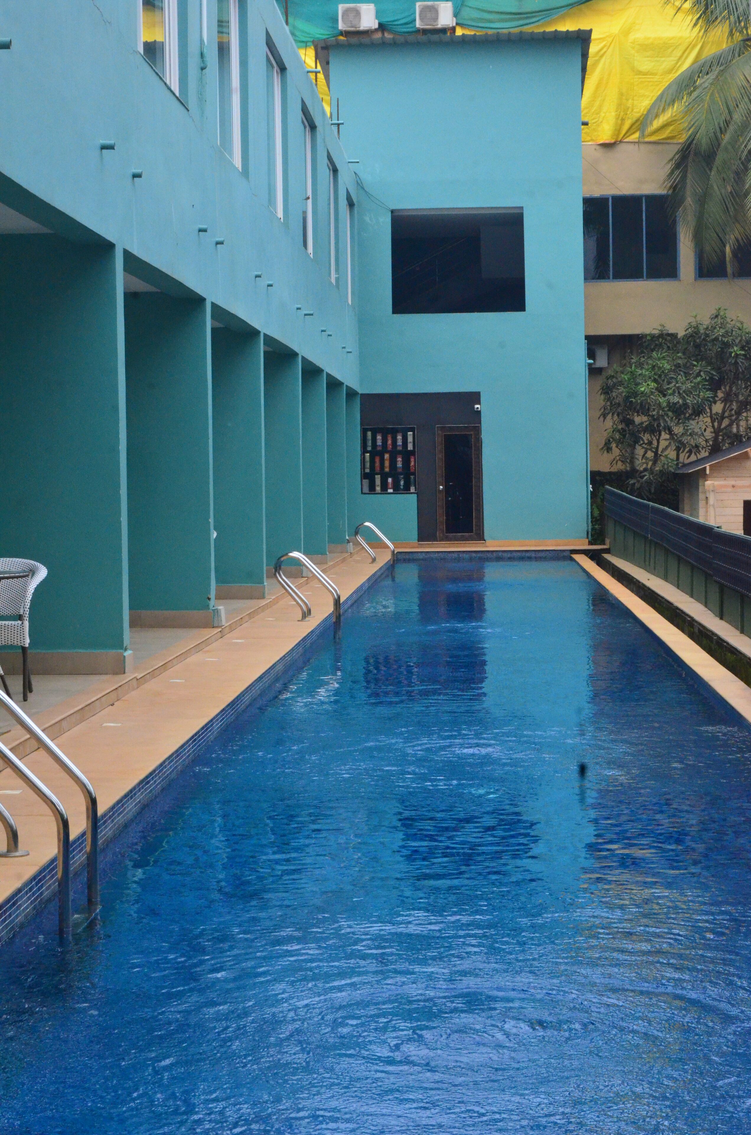 A swimming pool with a clear blue water, surrounded by teal walls and a yellow tarp.