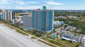 A high-rise hotel with a central courtyard, a pool, and a beach view.