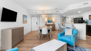 Een moderne woonkamer met een eethoek, een keuken en een aan de muur bevestigde televisie.