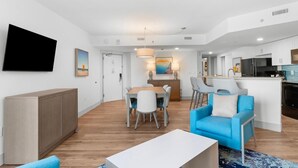 Een moderne woonkamer met een eethoek, een keuken en een aan de muur bevestigde televisie.