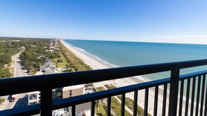 A coastal view from a balcony overlooking a beach with a road and buildings in the background. - Coastal Comfort Ocean View 2BDR Condo 19th Floor (Myrtle Beach)