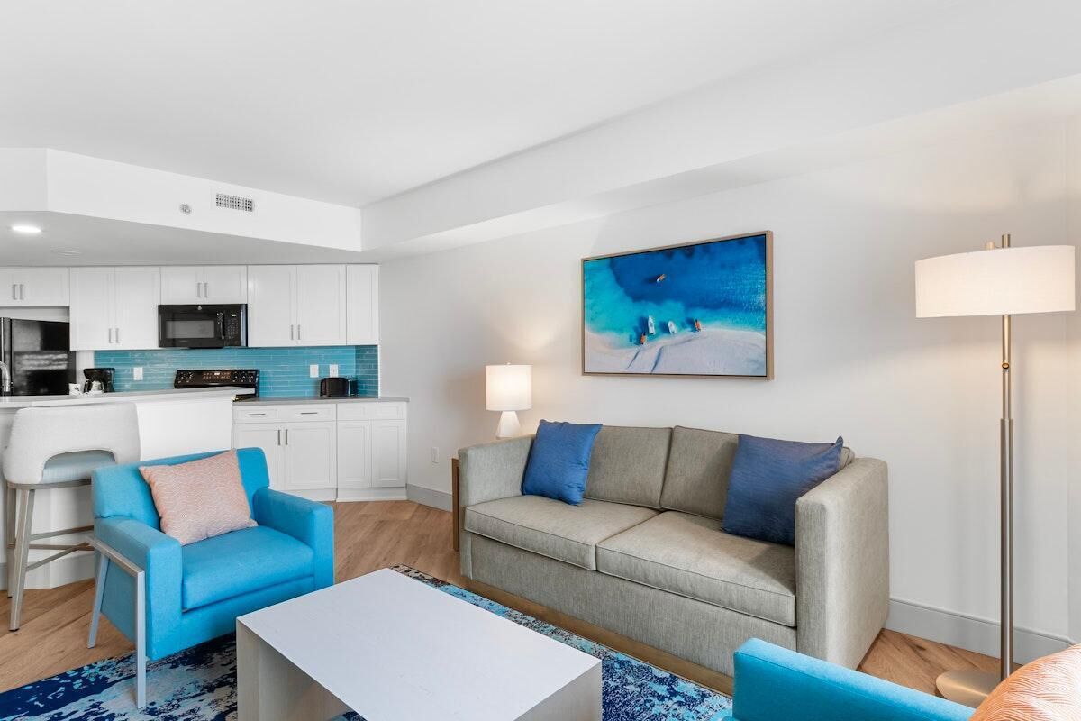 A modern living room with a sofa, a coffee table, and a painting on the wall.