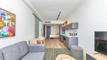 Ein modernes Wohnzimmer mit einem grauen Sofa, einem Holztisch und einem Fernseher auf einem Holzgestell.