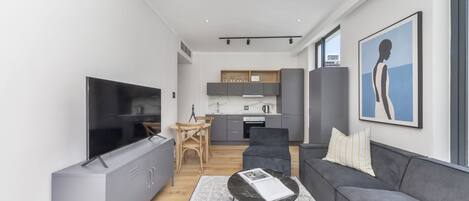 A modern living room with a grey sofa, a black coffee table, and a flat-screen TV.