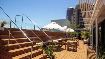 A wooden deck with outdoor seating, a staircase, and a glass balustrade.