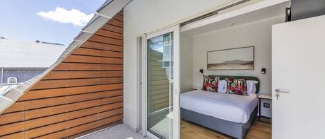 Un dormitorio moderno con cama, mesita de noche y un cuadro en la pared.