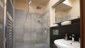 Ein modernes Badezimmer mit einer ein Glaswand abgetrennten Dusche, einer weißen Toilette und einem Waschbecken mit Spiegel darüber.