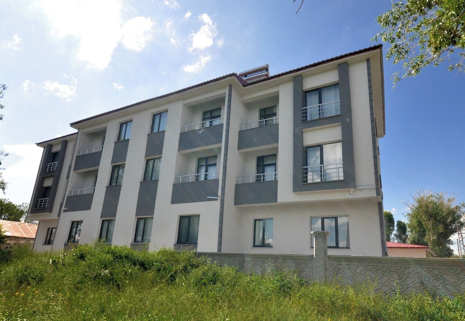 A multi-story residential building with balconies, large windows, and a flat roof.