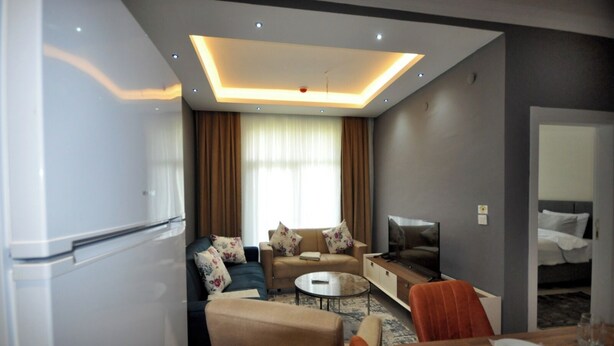 A modern hotel room with a sofa set, a TV, a dining table, and a minibar. - Arpaçay Apart Otel (Arpaçay)