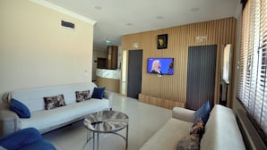 A modern hotel lobby with a reception desk, a flat-screen TV mounted on the wall, and a seating area with a sofa and a coffee table. - Arpaçay Apart Otel (Arpaçay)