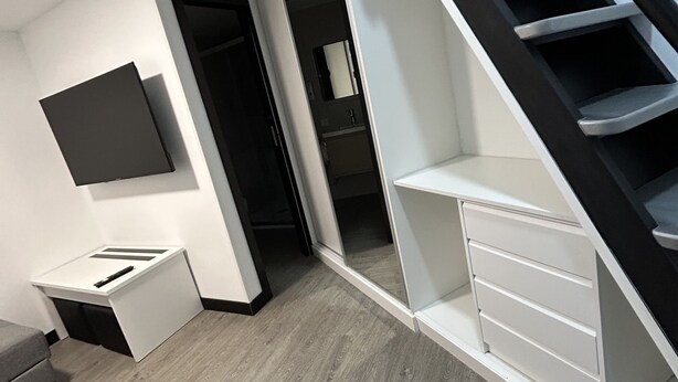 Eine moderne Wohnung mit Treppe, einem flachbildfernseher an der Wand und minimalistischem Design.