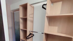 Ein begehbarer Kleiderschrank mit offenen Regalen und einer Kleiderstange.