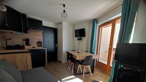 Ein kompakter Wohnbereich mit Küchenzeile, Essbereich, Sofa und Fernseher.