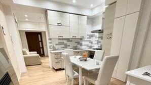 Une cuisine moderne avec des meubles blancs, une table à manger avec des chaises et un plancher en bois clair.