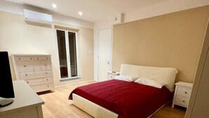 Une chambre à coucher comprenant un lit, un bureau, une chaise, une armoire et une porte-fenêtre coulissante.