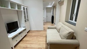 Un salon moderne avec un téléviseur à écran plat, un canapé et une fenêtre.
