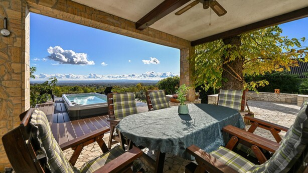 A covered patio with a hot tub, wooden furniture, and a view of the landscape. - Luxurious home in Vucetinec (Vucetinec)