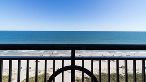 A beach view from a balcony with a railing, sandy beach, and clear blue sky. - Eighth Floor Elegance Spacious 3 Bedroom Condo (Myrtle Beach)