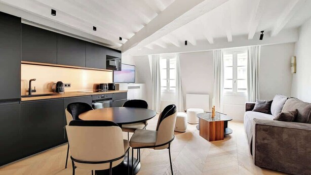 A modern kitchen with a dining area, a sofa, and a TV. - A Refined 1-BR appartment in Saint-Germain (Paris)