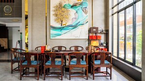 A dining area with a large table and chairs, a clock, and a painting on the wall. - Sunshine Hotel (Phnom Penh)