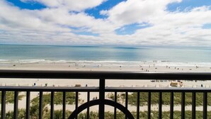 A beach view from a balcony with a railing, sandy beach, ocean, and a clear sky. - Seaside Splendor on the 6th Floor: 3 Bedroom Condo (Myrtle Beach)