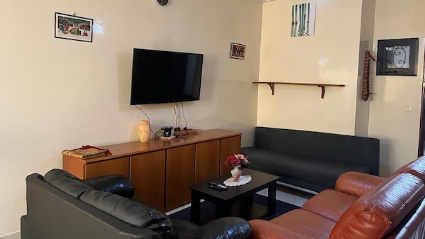 Ein Wohnzimmer mit Flachbildfernseher, Holzschrank, Sofa und Couchtisch.