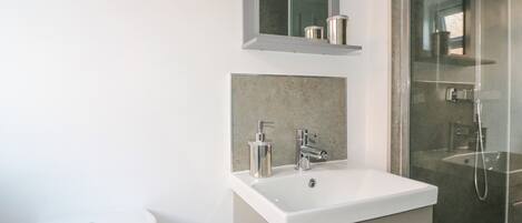 A modern bathroom with a white sink, a toilet, and a glass-enclosed shower area.