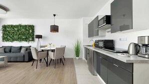 Een moderne keuken met een ingebouwde magnetron, een koffiezetapparaat en een waterkoker op het aanrecht.
